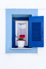 window with flowers and blue window frame in greece