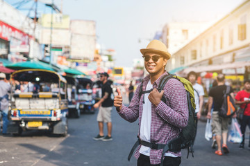 Young asian traveller man walking in Khaosan Road walking street in bangkok thailand on vacation time. - obrazy, fototapety, plakaty