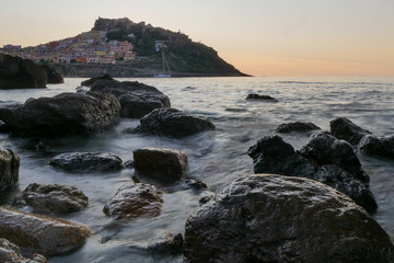 Fototapeta na wymiar castelsardo by sunset. blurry sea and rocks. italy. sardinia. 