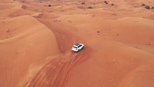 AERIAL. Top view of Four-wheel-drive car in the desert. Camera follows to bug white car in the desert