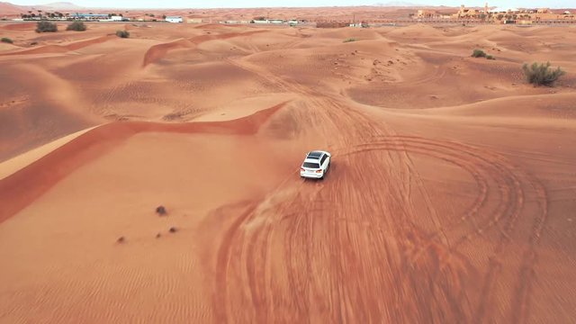 AERIAL. Top view of Four-wheel-drive car in the desert. Camera follows to bug white car in the desert