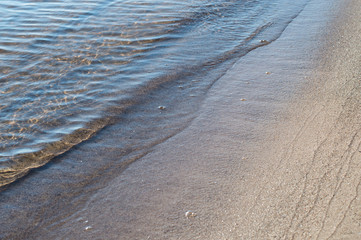 Sea water waves washing sandy beach