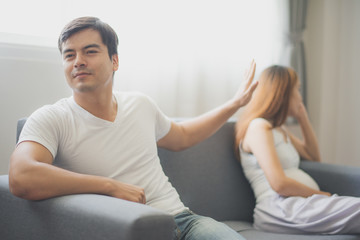 Young angry man and his pregnant wife are sitting on sofa at family's home. To be new Mother and Father, pregnant woman concept.