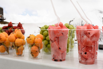Pieces of fresh fruit in glasses on background of Caucasus Mountains among the snows, Georgia