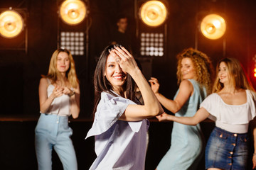 Shot of a young brunette woman dancing with her friends during holidays party relaxing celebrating dancing at party in night club together. Party, holidays, celebration, nightlife and people concept.