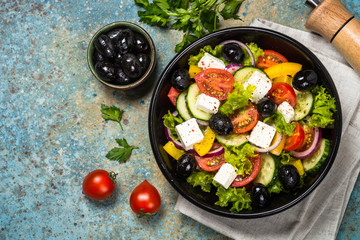 Greek salad in black plate on the table.