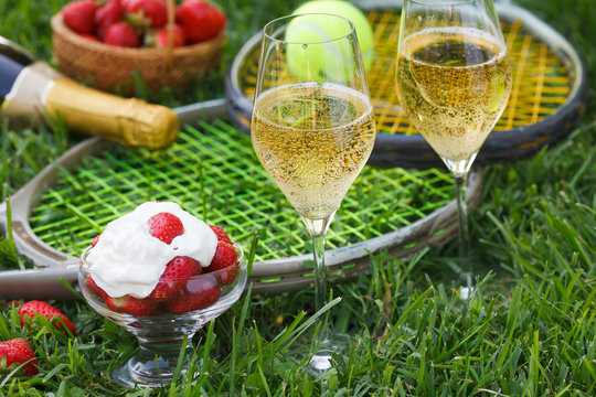 Enjoing in Wimbledon tennis championship with champagne and strawberries with cream. Wimbledon symbols on green grass.