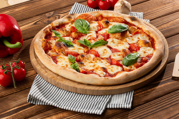 Pizza Margherita on wooden background, top view. Pizza Margarita with Tomatoes, Basil and...
