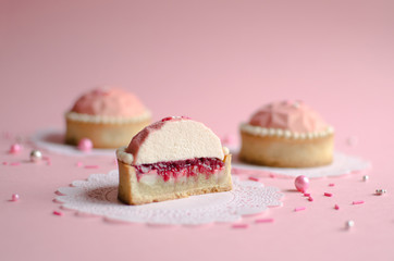 Mousse mini tarts covered with pink velvet spray decorated with sugar balls on pink background