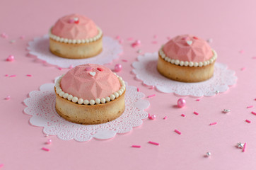 Mousse mini tarts covered with pink velvet spray decorated with sugar balls on pink background