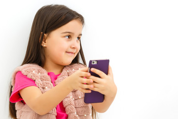 Fototapeta premium Little girl holding a smart phone against white background