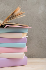 Education and reading concept - group of colorful books on the wooden table, concrete wall blackboard