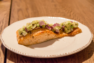 Salmon Fillet with Avocado in Plate at Dinner Table.