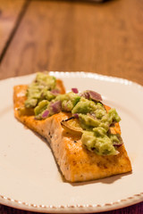 Salmon Fillet with Avocado in Plate at Dinner Table.