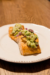 Salmon Fillet with Avocado in Plate at Dinner Table.