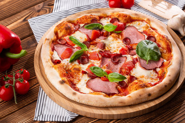 Pizza with ham , arugula (salad rocket), rucola and mozzarella  on  wooden background close up. Italian cuisine.