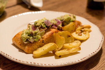 Salmon Fillet with Avocado in Plate at Dinner Table.