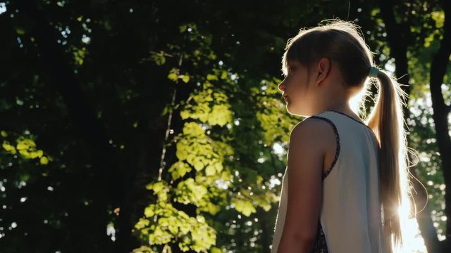 The child stands in the beam, the sun is shining on her face. Get lost in a fairy forest