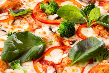 Vegetarian pizza on a wooden background with mushrooms, broccoli, cheese and sweet pepper and basil. Top view.