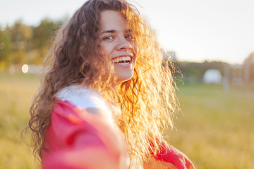 Happy curly charming girl with long curly hair and a very beautiful smile, summer portrait