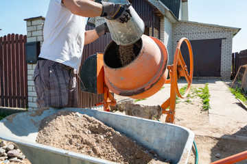 builder working with shovel during concrete cement solution mortar preparation. construction worker...
