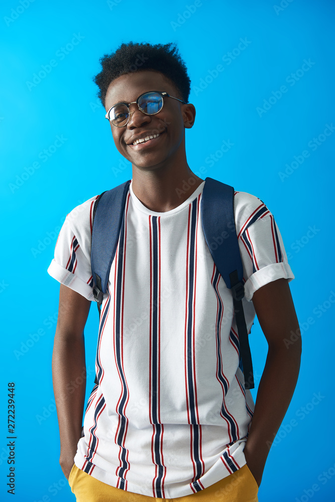 Wall mural Happy Afro student is standing with backpack