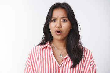 Fototapeta premium Concerned female friend hearing disturbing news feeling empathy and pitty standing worried and upset frowning open mouth, feeling sorry for terrible situation happening standing against white wall