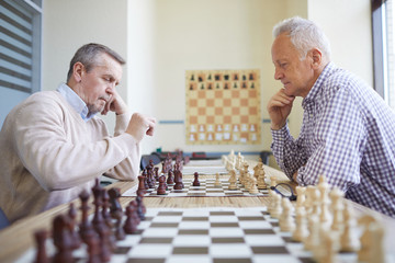 Two aged experienced chess players with silver hair playing chess at professional chess tournament