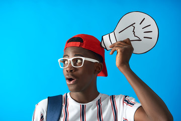 Surprised afro student wearing striped t-shirt and red cap