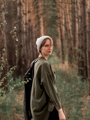 Stylish young woman posing in nature in street style clothing.