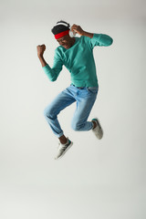 Positive young man with red bandage is dancing in studio