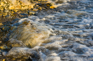 pebble stones on the sea beach, the rolling waves of the sea with foam