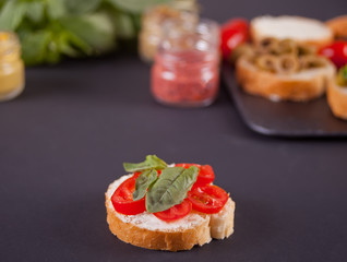 Italian bruschetta with cream cheese, tomato cherry and bazil and bruschetta in assortment on the plate with set with small bottle of mustard