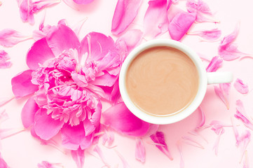 White cup of coffee with milk and pink peony flower with petals on a light beige background. Good morning. Close up. Top view. Flat lay