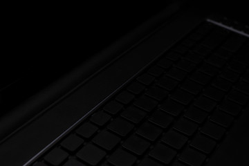 Close-up - an open laptop with a dark screen on a dark background.