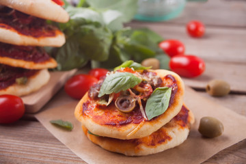 Homemade mini pizza on the wooden background.