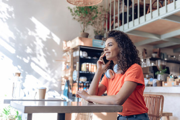 Happy girl is speaking on phone in bar