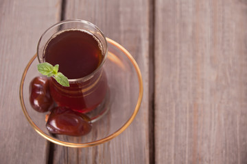 Turkish tea in traditional glass cup with date fruits on the table
