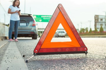 Asian teenage women holding a mobile phone Walking around the car, stressful mood during the evening hours. Along the highway Because her car broke down And she is waiting for help from someone.