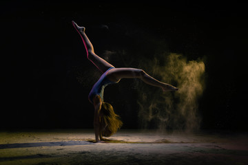 Female dancer doing handstand under colorful light