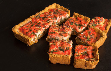 Rectangular quiche with salmon, spinach and cream on a black wooden table. French cuisine.