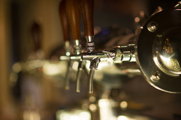 Fototapeta na wymiar Three vintage golden beer taps in the bar, blurry background. Detail on beer faucet.