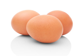 Three brown chicken eggs isolated on white background with shadow reflection. Three brown chicken eggs on white background. Trio of eggs on white background. Three brown chicken eggs on white