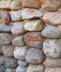 Garden fence of large natural round stones. Cobblestone wall. Background.