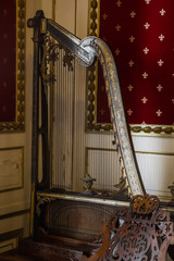 A piano with a harp stands in the corner of a luxury room with vintage wallpaper. baroque interior...