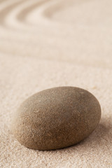 Fototapeta na wymiar Zen garden meditation stone. Round rock on sandy texture background.
