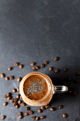 Organic natural chocolate coffee cacao smoothie beverage with chia seeds in glass jar on a black graphite slate background with coffee beans, top view. Healthy diet vegetarian snack. Free copy space