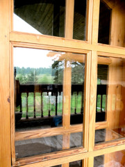 Reflection of field and forest in the wooden window