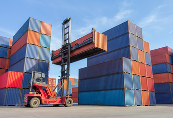 Forklift handling container box loading to truck in shipping yard with cargo container background.