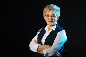 beautiful stylish aged woman in glasses in waistcoat on black background